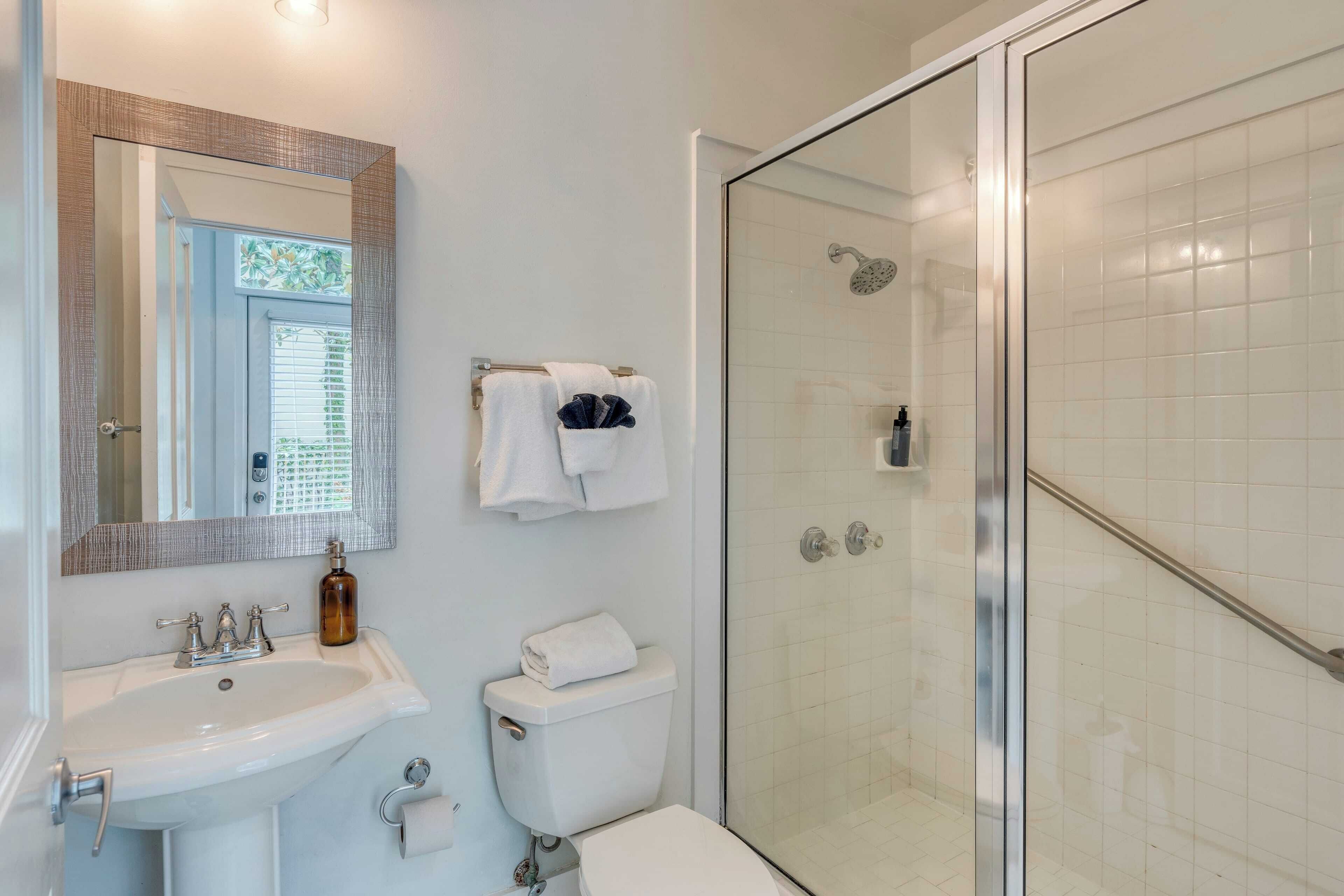 A bathroom with a white sink, a mirror, a toilet, and a glass-enclosed shower.