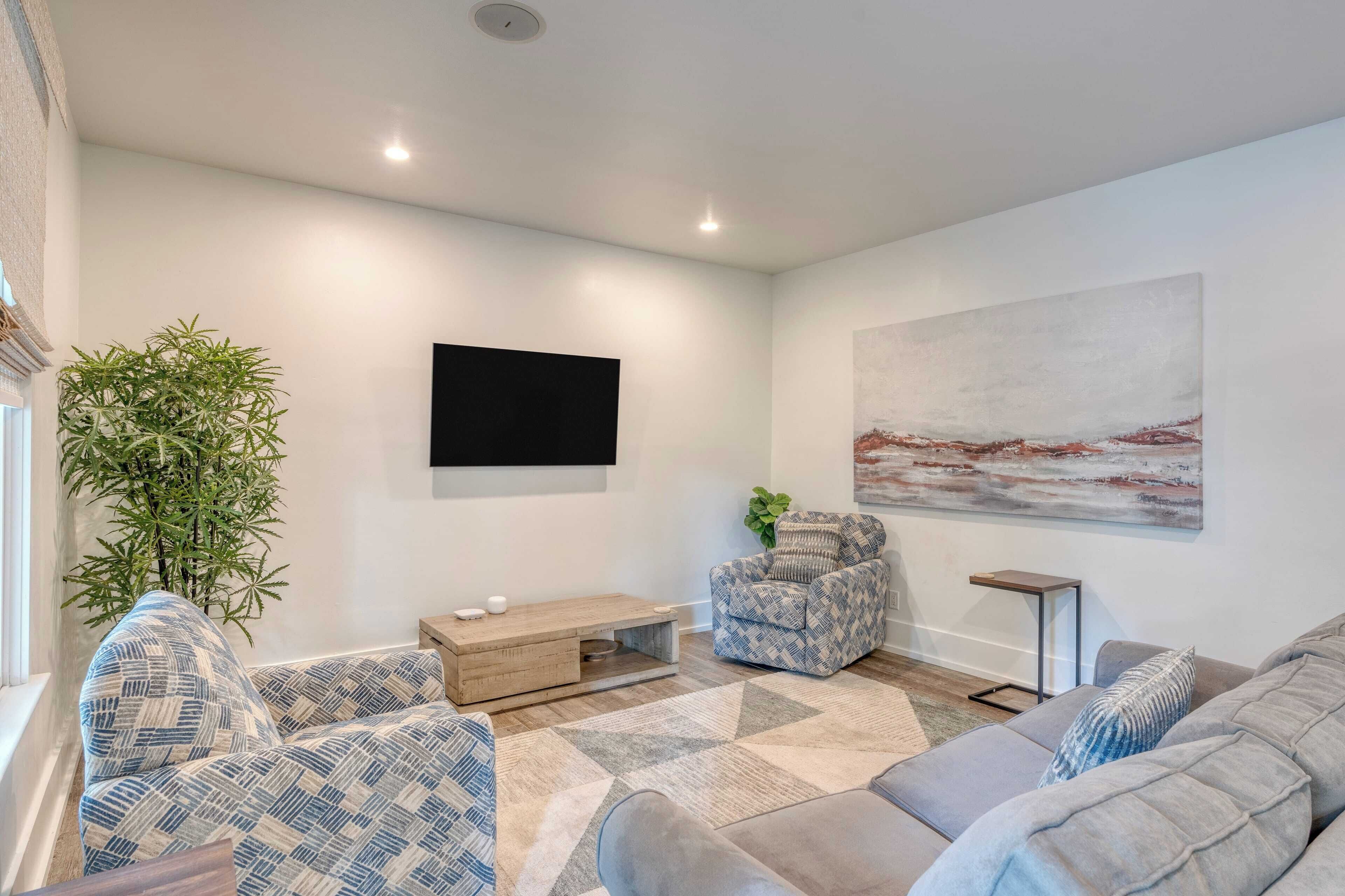 Una sala de estar moderna con un sofá, un sillón, una mesa de centro y un cuadro grande en la pared.