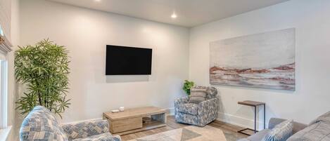 Una sala de estar moderna con un sofá, un sillón, una mesa de centro y un cuadro grande en la pared.