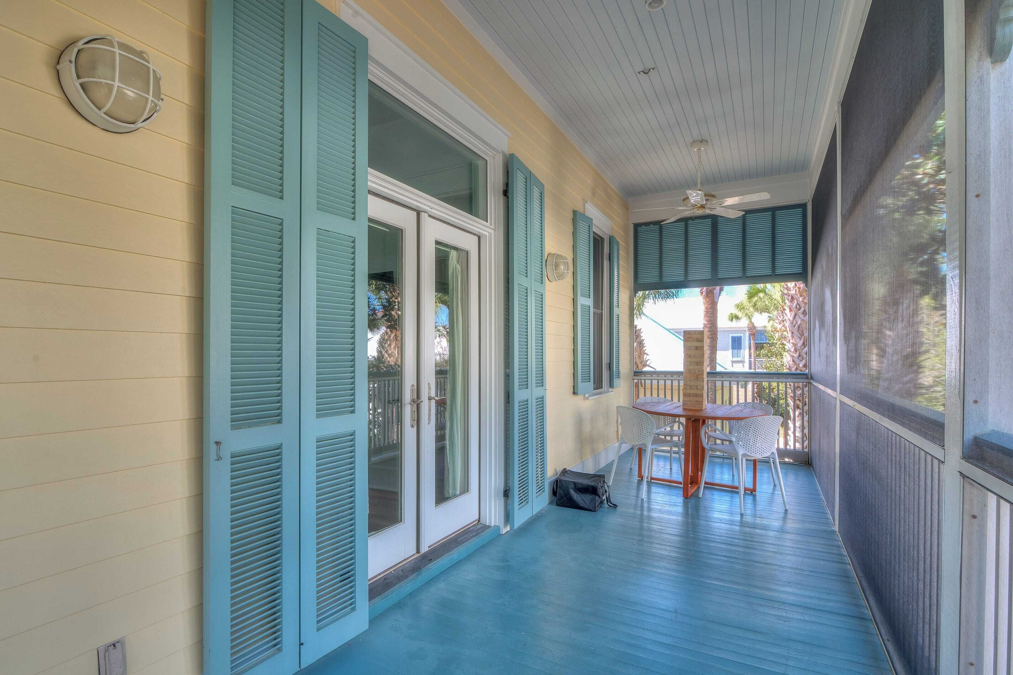 A covered porch with a table and chairs, a ceiling fan, and a view of the outside.