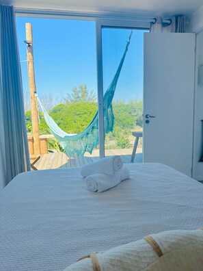 Relax in this serene retreat with a large bed and access to an outdoor space featuring a hammock.