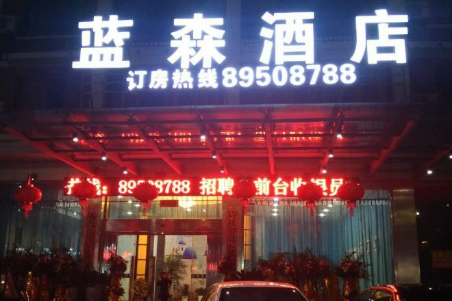 A hotel entrance with a neon sign displaying the name and contact number.