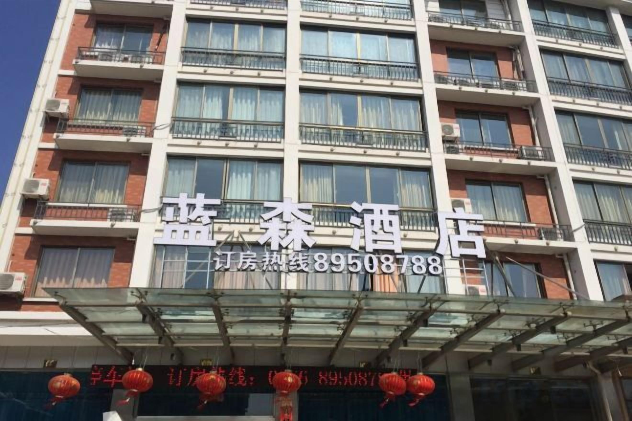 Un edificio de hotel de varios pisos con balcones y una señalización clara que muestra el nombre y el número de contacto.