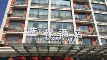 Un edificio de hotel de varios pisos con balcones y una señalización clara que muestra el nombre y el número de contacto.