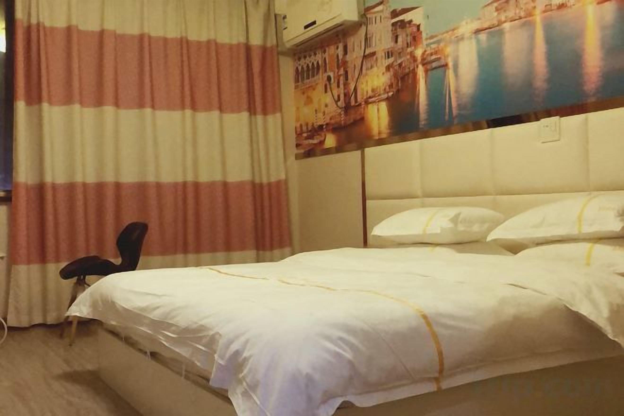 Quarto de hotel com cama, cadeira e pintura de uma paisagem urbana na parede.