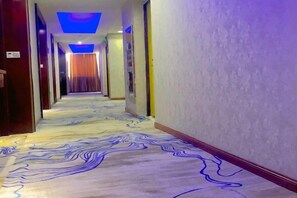 A hotel corridor with a patterned carpet, doors on the left, and a plain wall on the right. - Blue Sen Hotel (Tiantai Mountain Scenic Area) (Tiantai County)