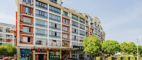 A multi-story hotel with a modern facade, balconies, and a ground-level restaurant.
