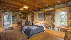 Une chambre confortable avec un grand lit, des étagères en bois, un bureau et une fenêtre donnant sur un beau paysage.