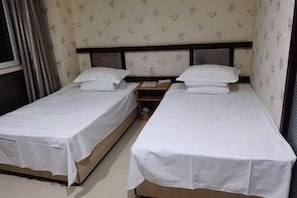 A room with two single beds, each with a wooden headboard and white bedding. - Baihequan Hotel (Antu)