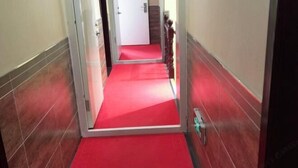 Un couloir recouvert d’une moquette rouge, qui mène à une porte au fond.