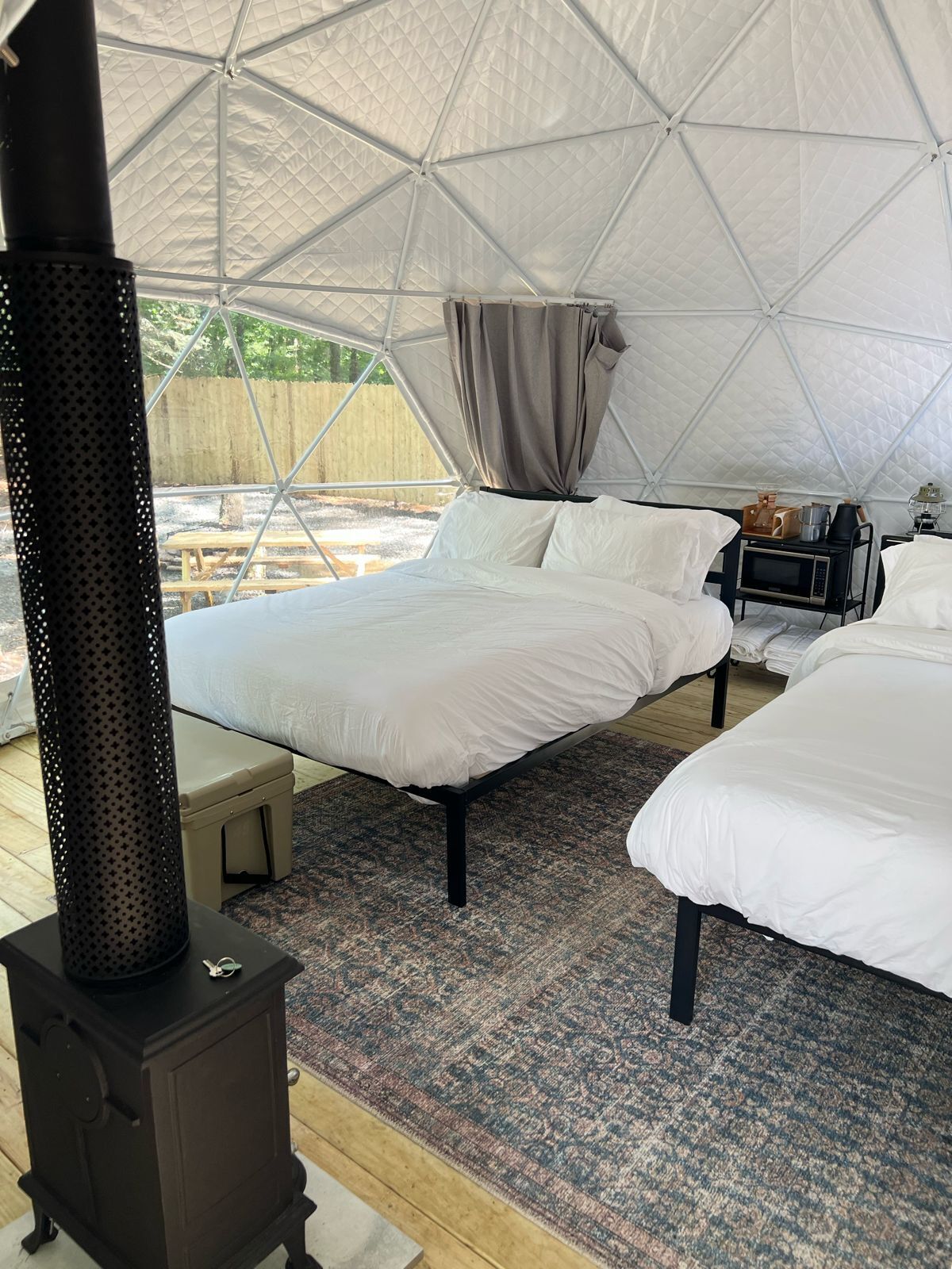 Alojamiento en tienda de campaña con dos camas, una estufa y una pequeña mesa con un hervidor.