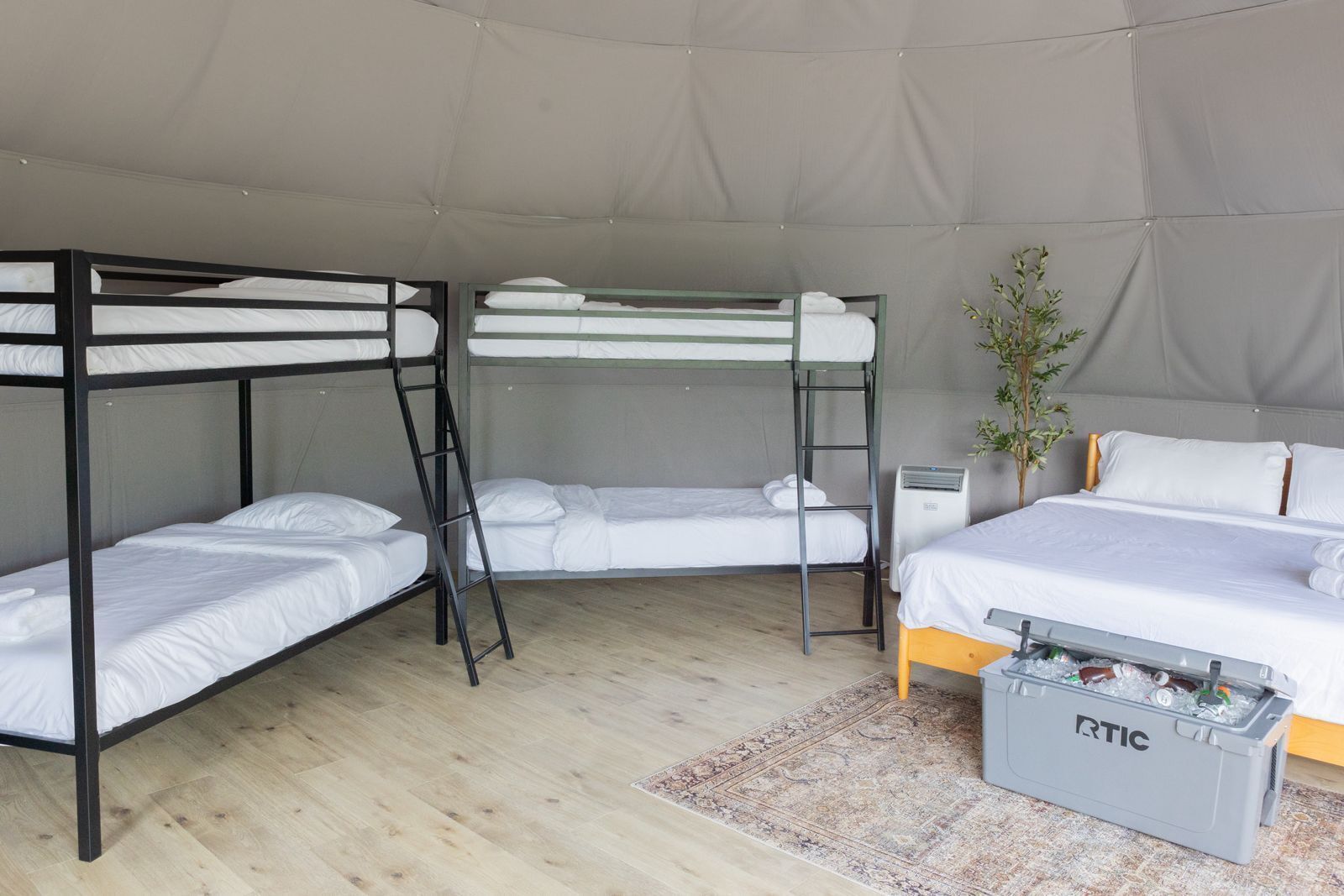 Een tentruimte met stapelbedden, een enkel bed, een kleine verwarming en een opbergkist.