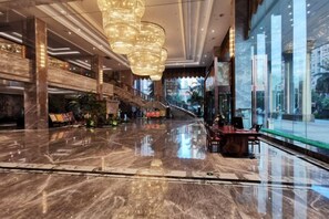 A spacious lobby with a marble floor, a grand staircase, and large windows offering a view of the city. - CHOUERY International Hotel (Wenzhou)