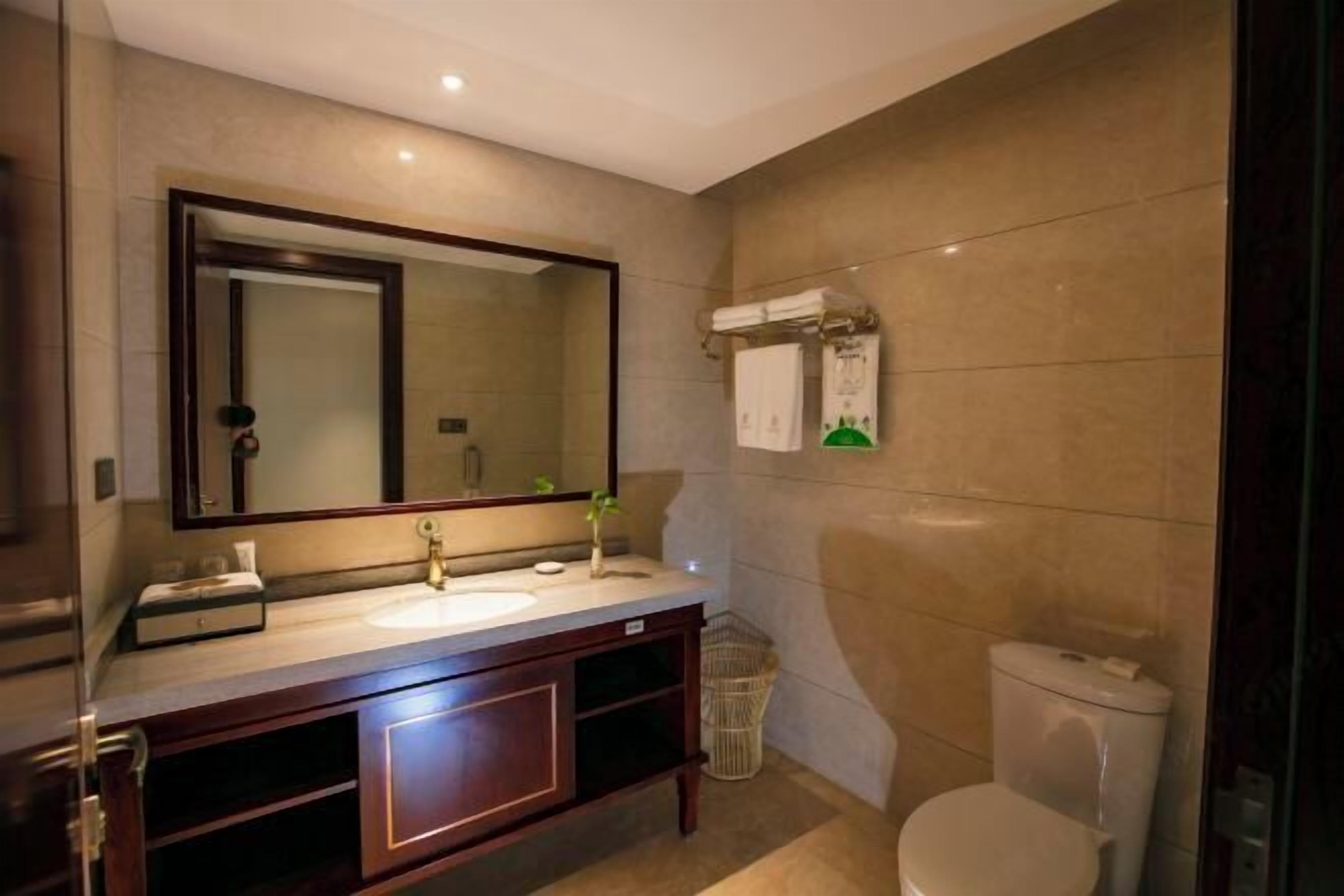 A modern bathroom with a large mirror, a sink, and a toilet.