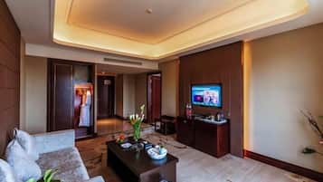 A modern hotel room with a sofa, a coffee table, a TV, and a decorative vase.