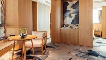 A modern hotel lobby with a wooden reception desk, a seating area with a sofa, and a decorative wall piece.