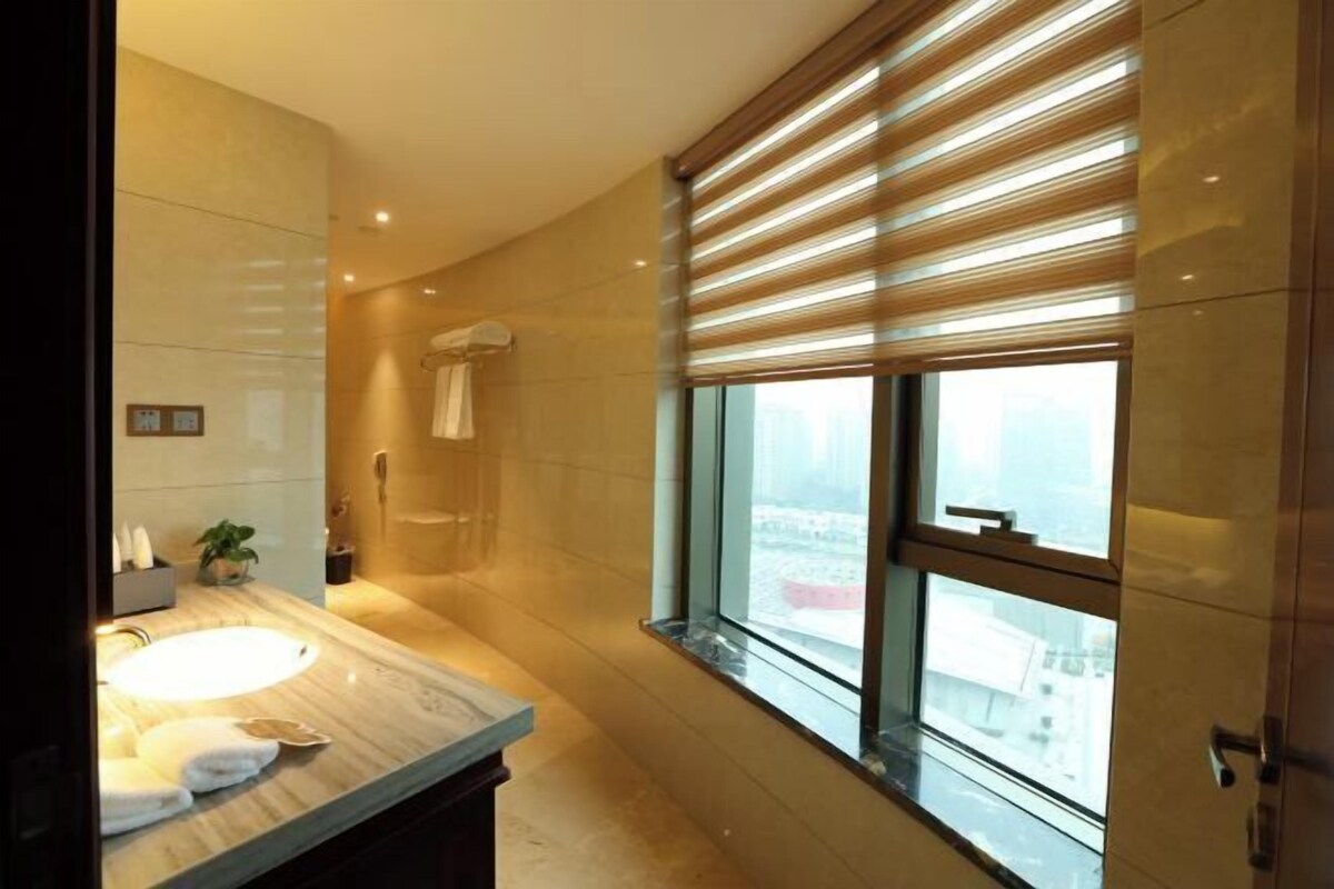 A modern bathroom with a large window, a marble sink, and a towel rack.