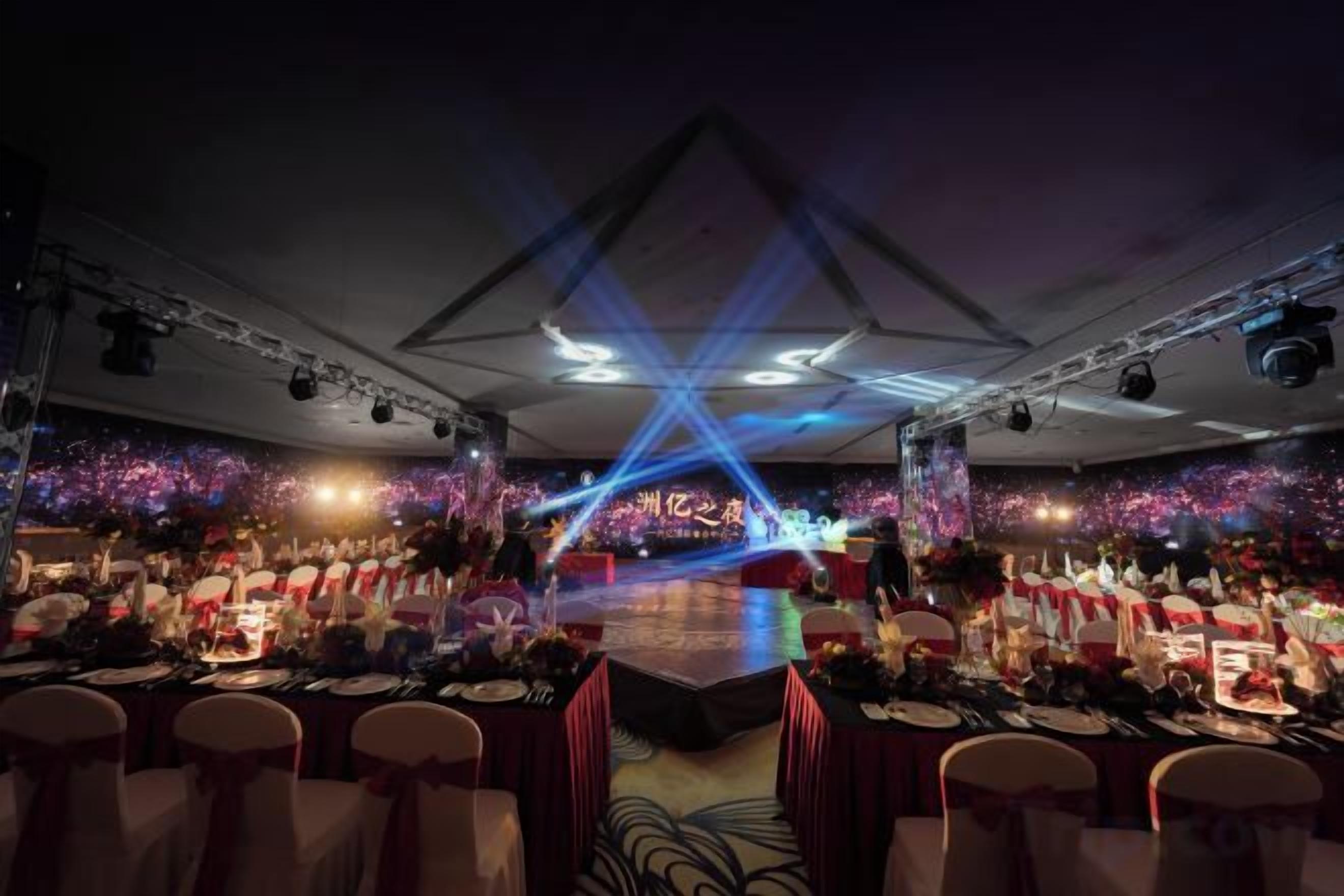 A banquet hall with tables set for a formal event, stage lighting, and a large screen.