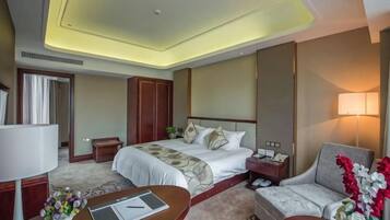 A hotel room with a bed, bedside table, lamp, and a sofa.