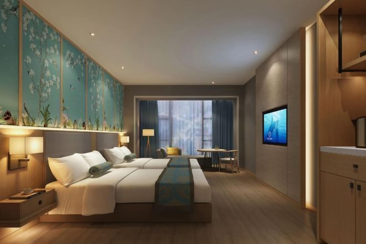 A modern hotel room with a large bed, a desk, a TV, and a view of the outdoors.