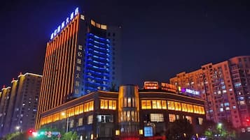 A multi-story hotel with illuminated signage, a prominent entrance, and surrounding high-rise buildings.