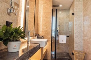 A modern bathroom with a marble countertop, a sink, a glass shower enclosure, and a potted plant. - CHOUERY International Hotel (Wenzhou)