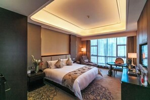 A hotel room with a large bed, a desk, a chair, a small table, and a large window. - CHOUERY International Hotel (Wenzhou)