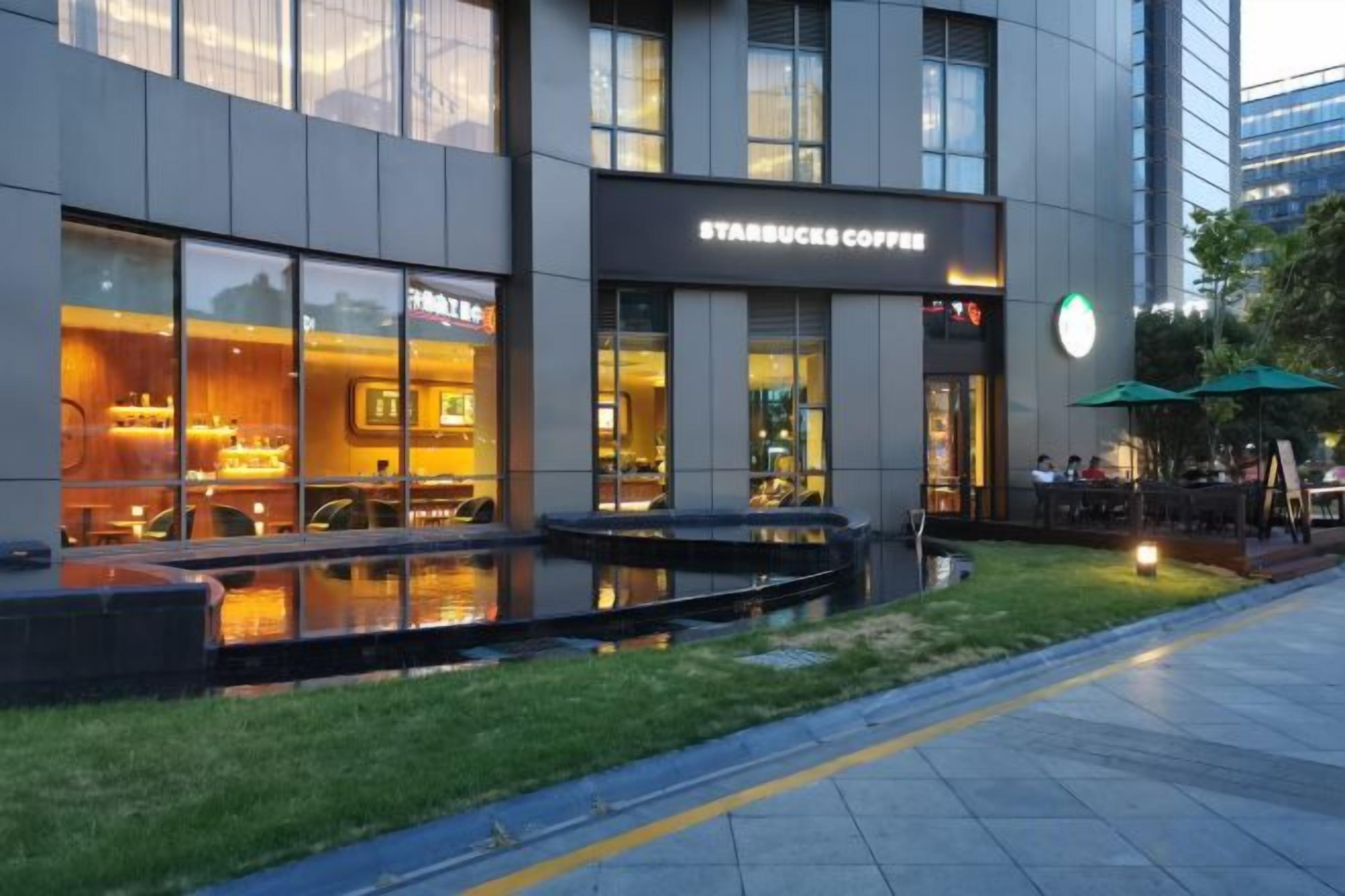 A Starbucks Coffee store with outdoor seating and a water feature in front.