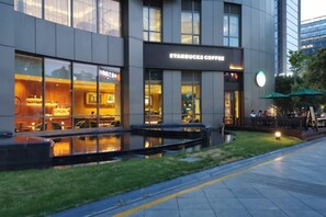 A Starbucks Coffee store with outdoor seating and a water feature in front. - CHOUERY International Hotel (Wenzhou)