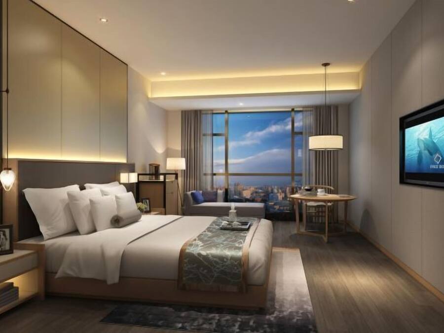 Una habitación de hotel moderna con una cama grande, un escritorio y vistas a la ciudad.