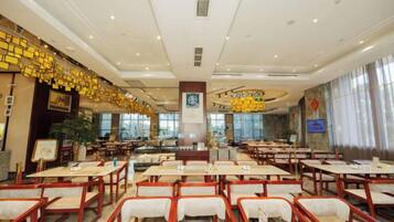 A spacious restaurant with multiple tables and chairs, a central pillar, and a large window providing natural light.