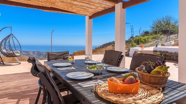 An outdoor dining area with a table set for four, overlooking a scenic coastal view. - Casa Rueapara Torrox by Ruralidays (Málaga)