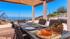 An outdoor dining area with a table set for four, overlooking a scenic coastal view. - Casa Rueapara Torrox by Ruralidays (Málaga)
