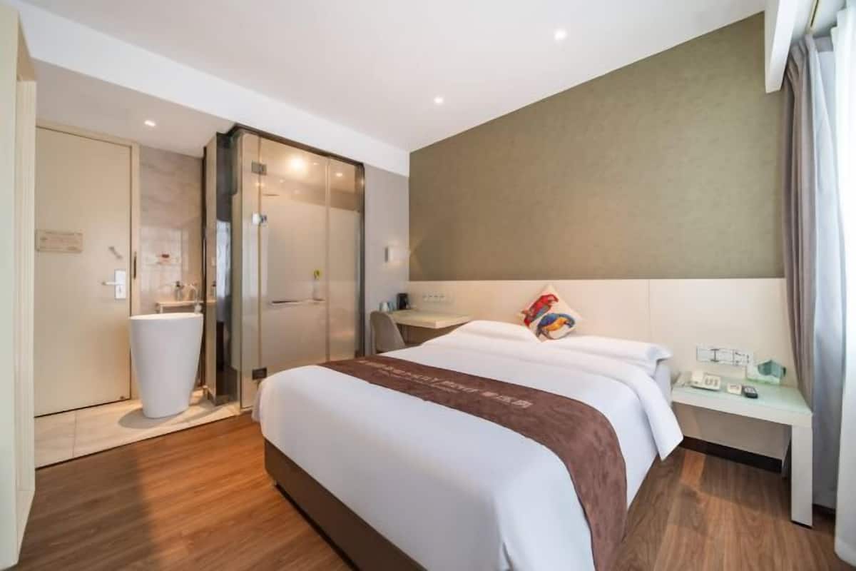 Una habitación de hotel con una cama grande, un escritorio, un espejo y una zona de ducha.