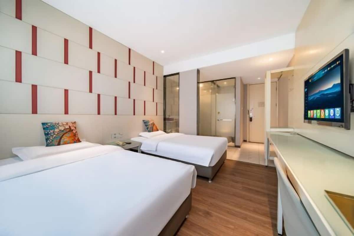Una habitación de hotel con dos camas, un televisor de pantalla plana y un diseño de pared moderno.
