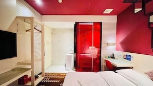 A hotel room with a bed, a TV, a desk, a shower area, and a red accent wall. - Yue Yue Scenic View Hotel(Zhengzhou Boudou·Xinxiang Confucius Temple Metro Station Store) (Zhengzhou)