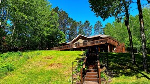 Eine Holzhütte mit einer Terrasse und einer Treppe, die zu einer Veranda führt.