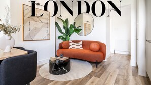 A modern living room with a sofa, coffee table, and a large mirror. - Stylish Modern Designed Apt, near Station, London (Northwood)