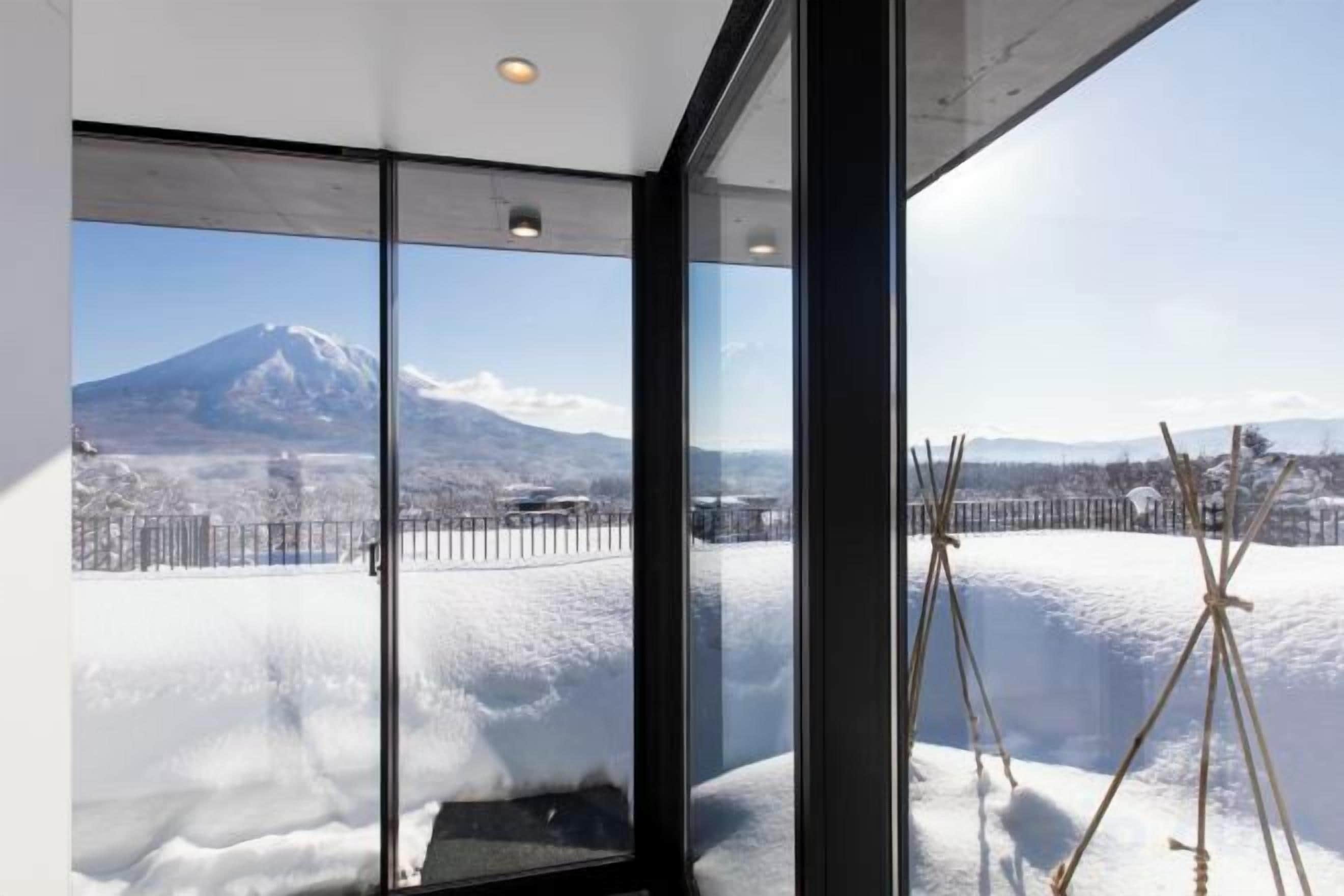 A room with large windows offering a view of a snow-covered landscape and a mountain.