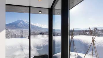 A room with large windows offering a view of a snow-covered landscape and a mountain.