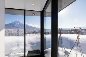 Una stanza con ampie finestre che si affacciano su un paesaggio innevato e una montagna.
