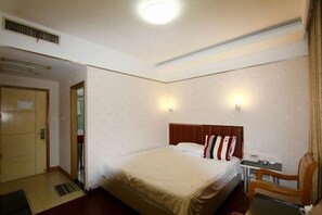 A hotel room with a bed, a desk, a chair, and a door. - Century Express Hotel (Tongxiang)