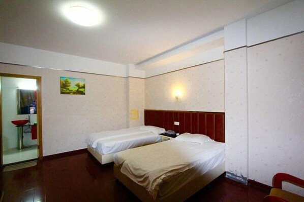 A hotel room with two beds, a red headboard, a small bedside table, a wall-mounted light, and a painting on the wall. - Century Express Hotel (Tongxiang)