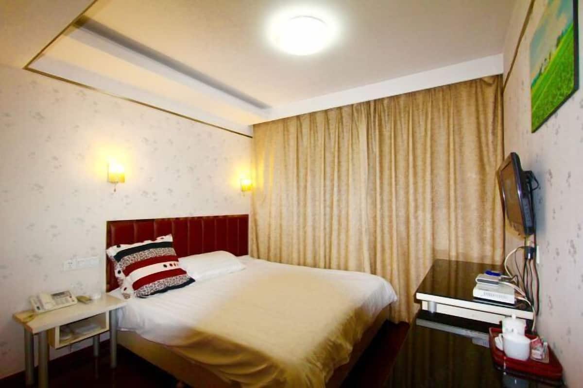 Una camera d'albergo con un letto, un comodino, una lampada e un televisore.