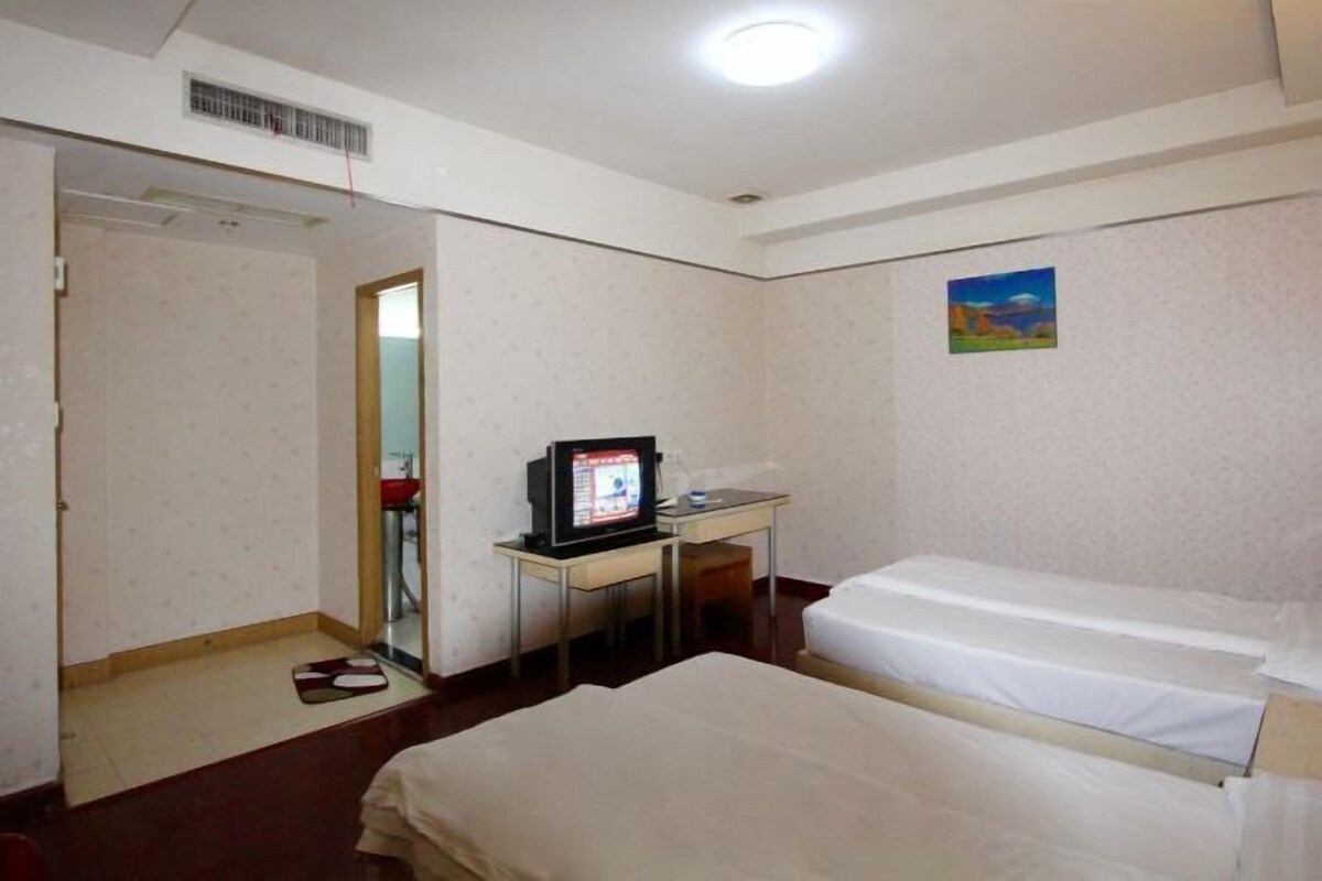 A hotel room with two beds, a desk with a computer, a mirror, and a painting on the wall.