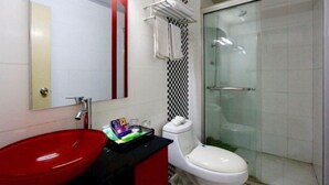 Ein Badezimmer mit einem roten Waschbecken, einer weißen Toilette und einer Duschkabine aus Glas.