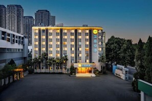 A multi-story hotel with a modern facade, a central entrance, and a parking area in front. - Hanting Express Zhengzhou Zhenghenghui Dongqing Street Subway Station Hotel (Zhengzhou)