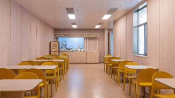 A dining area with tables and chairs, a counter with a menu, and a window providing natural light.