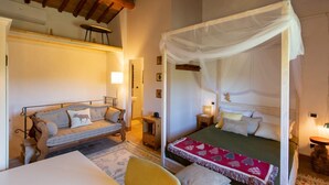 Un dormitorio con una cama con dosel, un sofá y una mesita.