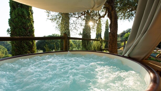 Un jacuzzi con vistas a árboles y una terraza de madera.
